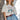 Eesome American Cowgirl Club graphic tee in Bone — star-patterned boots print, red cross-stitch neckline. Front on-model.